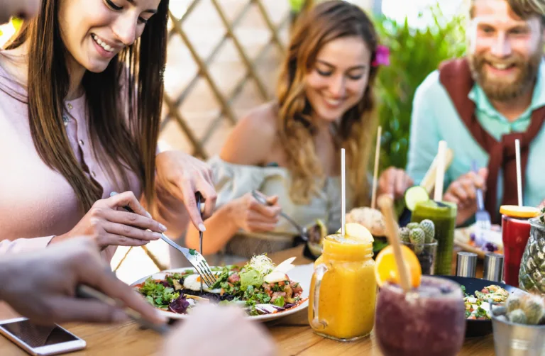 Happy friends lunching with healthy food in bar coffee brunch - Young people having fun eating meal and drinking fresh smoothies in restaurant - Health nutrition lifestyle concept
