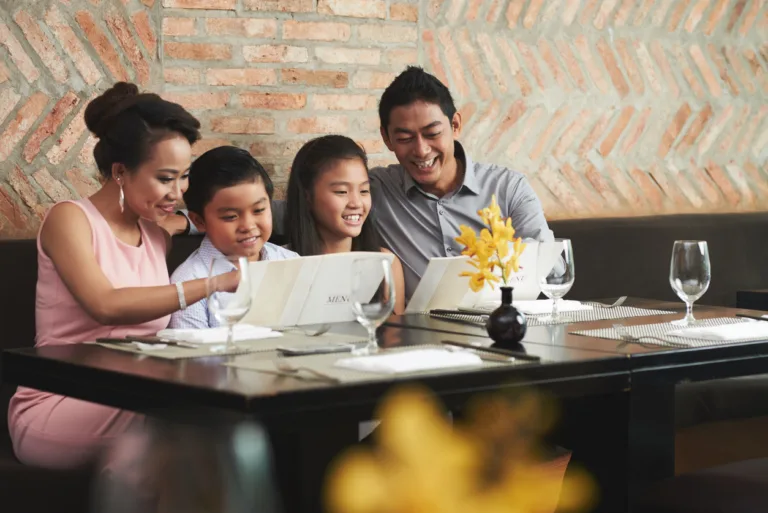 Smiling Vietnamese family reading menu at restaurant
